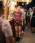 Frau trägt HangOwear DILARA T-Shirt weinrot mit goldenem Herz-Madl-Druck am Festzelt-Stand