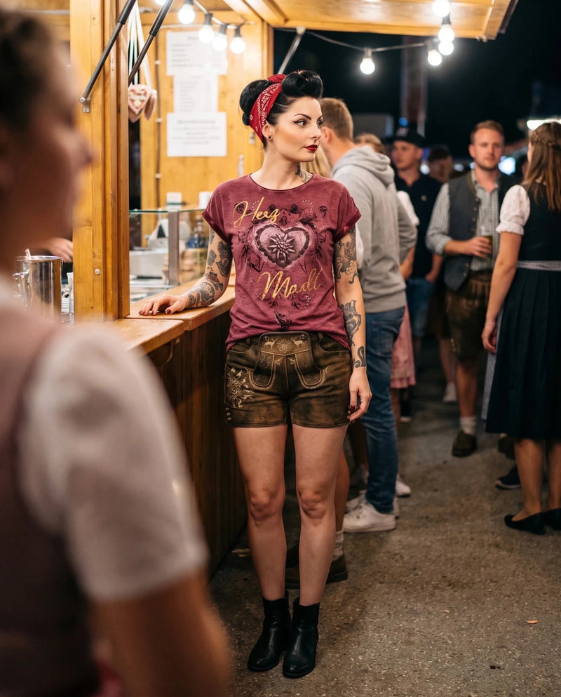 Frau trägt HangOwear DILARA T-Shirt weinrot mit goldenem Herz-Madl-Druck am Festzelt-Stand